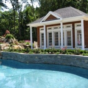 Beautiful outdoor pool with cabanas and lush landscaping in Long Island.