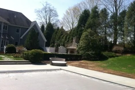 Elegant outdoor living space featuring a pool, outdoor furniture, and landscaped yard on Long Island. Beautiful backyard with pool, outdoor furnishings, and lush landscaping.