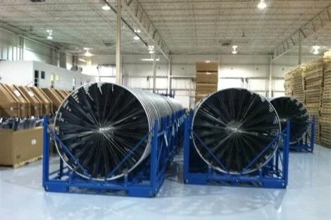 Solar panel rolls stored in a warehouse, ready for installation or distribution. Large black solar panel rolls stored in a warehouse with industrial shelving.