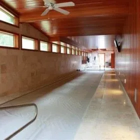 Indoor pool with cover, wooden walls, and natural light from windows.