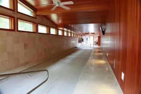 Indoor pool with automatic cover, wooden walls, and natural lighting, perfect for year-round swimming. Indoor pool with wooden walls and automatic cover, Long Island.