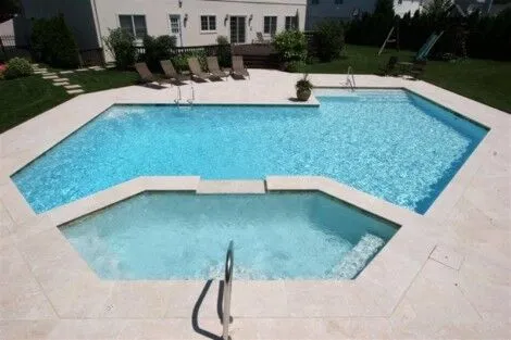 Custom geometric gunite pool with attached hot tub, perfect for outdoor entertaining on Long Island. Modern geometric gunite pool with attached hot tub on Long Island.