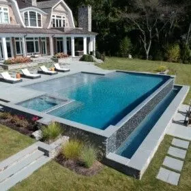 Luxury inground pool with vanishing edge and outdoor lounging area.