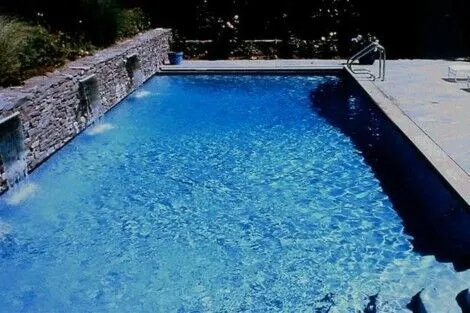 Luxury inground pool with waterfall feature and outdoor lounge on Long Island. Beautiful inground pool with stone waterfall and outdoor seating area.