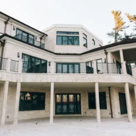 Modern multi-level house with large windows and balcony railings.