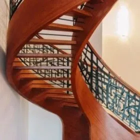 Beautiful wooden spiral staircase with black metal railing in modern home.