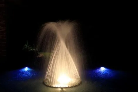A beautifully lit fountain at night with water jets and colorful lighting effects. Nighttime fountain with colorful lighting and water jets.