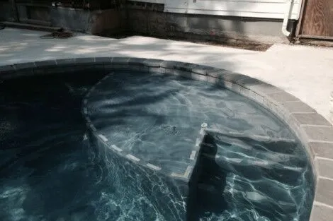Custom inground pool with stone coping and outdoor furnishings in Long Island, perfect for outdoor living. Inground pool with stone coping and outdoor patio in Long Island.