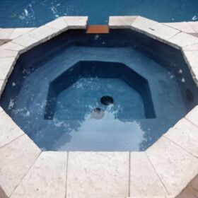 Inground hot tub with stone surround and steps on Long Island.