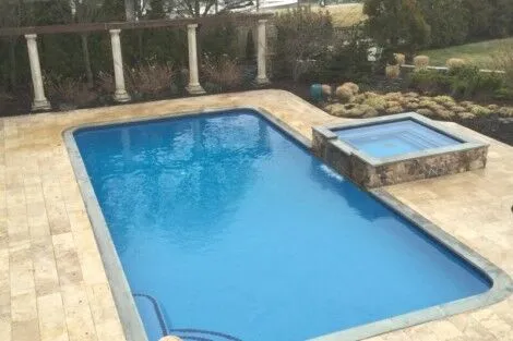 Elegant inground pool with hot tub, perfect for outdoor relaxation and entertaining in Long Island. Beautiful inground pool with attached hot tub on a landscaped patio.