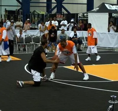 Basketball players in action during an indoor exhibition event with spectators in the background. Players competing in an indoor basketball game at a sports exhibition.