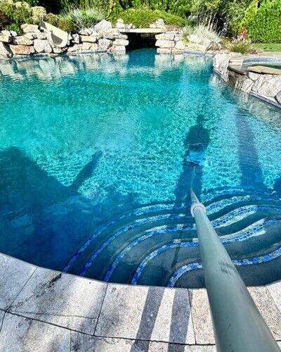 Luxury inground pool with stone accents and outdoor seating area in Long Island, perfect for outdoor living. Beautiful inground pool with stone border and outdoor furnishings in Long Island.