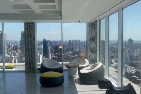 Spacious NYC apartment featuring floor-to-ceiling windows and contemporary furniture with stunning skyline views. Modern high-rise apartment with panoramic city skyline views.
