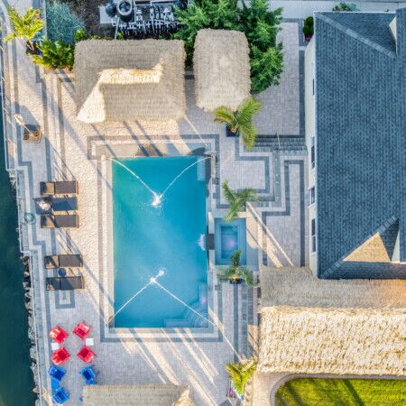 Aerial view of a Long Island pool with outdoor furniture and lush landscaping.