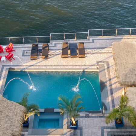 Aerial view of a luxurious pool area with loungers and tiki huts in Long Island.