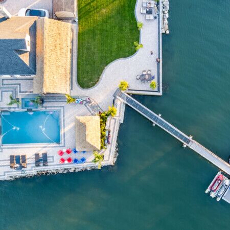 Aerial view of a waterfront property with pool, dock, and boat in Long Island.