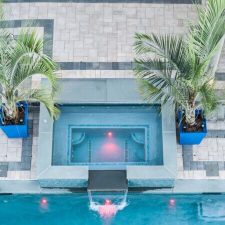 Inground pool with water features and surrounding outdoor furnishings.