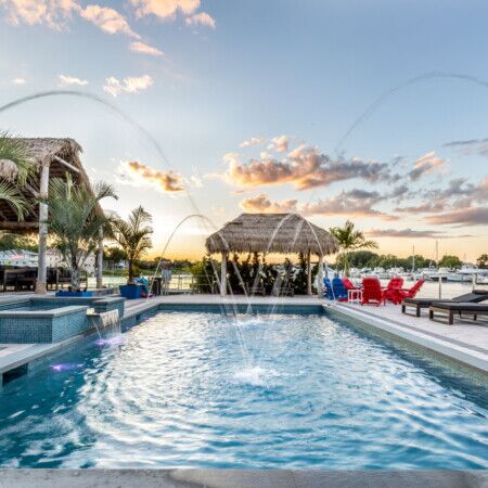 Luxury inground pool with outdoor furniture and tropical landscaping.
