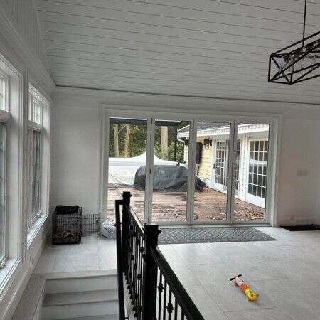 Sunroom with expansive windows and sliding door leading to backyard patio area. Sunroom with large windows and sliding glass door overlooking backyard.