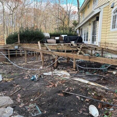 Ongoing backyard construction with wooden framework and construction debris in Oyster Bay. Construction site with wooden framework and debris in backyard.
