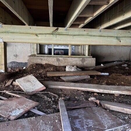 Construction site for an in-ground pool with wooden framing and building materials in Oyster Bay area. Underneath view of a backyard pool installation with wooden framing and construction debris.