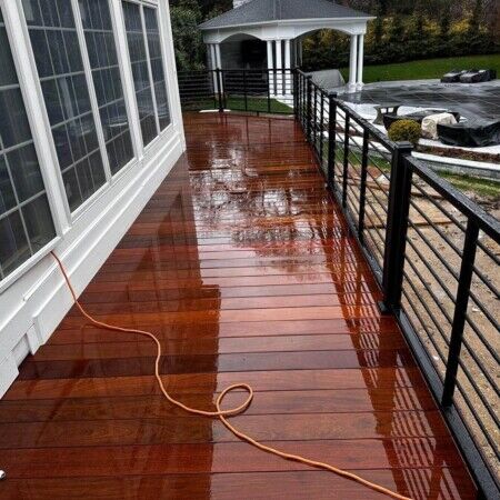Refined backyard with newly installed wet wooden deck, black railing, and outdoor gazebo in Long Island. Beautiful wet wooden deck with black metal railing and view of backyard.