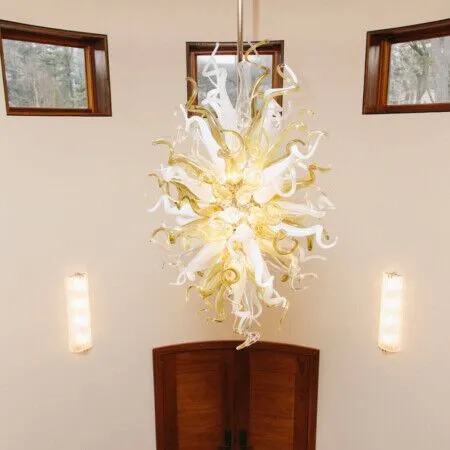Modern chandelier with white and gold design hanging in a bright room.