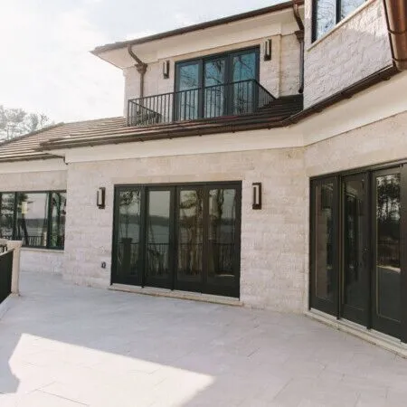 Modern house exterior with large glass doors and balcony.