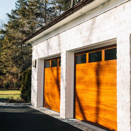 Beautiful wooden garage doors on a white brick house in Long Island.