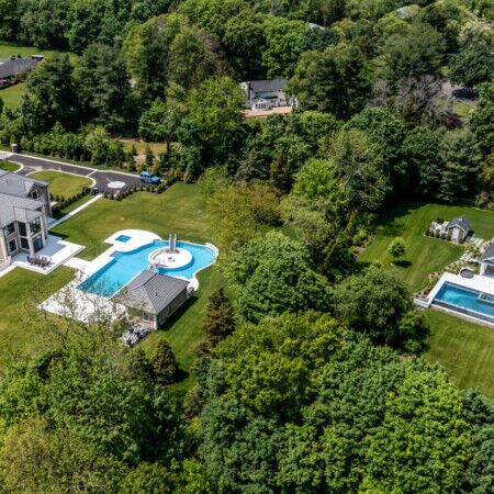 Elegant Long Island backyard featuring an inground pool, outdoor furnishings, and lush landscaping. Aerial view of a luxurious Long Island backyard with inground pool and outdoor furnishings.