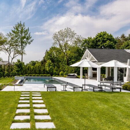 Elegant outdoor space with inground pool, patio, and lush landscaping in Syosset, Long Island. Beautiful backyard with inground pool, patio, and outdoor furnishings in Syosset.