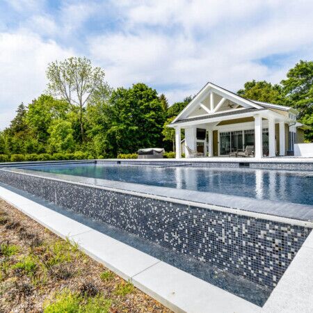 Elegant inground pool with surrounding outdoor living space in Long Island, perfect for outdoor entertaining. Luxury inground pool with modern design and outdoor furnishings in Long Island.
