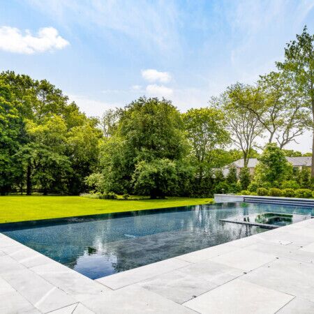 Elegant inground pool with surrounding outdoor furnishings, perfect for outdoor relaxation and entertainment in Long Island. Luxury inground pool with modern outdoor furnishings on a sunny day.