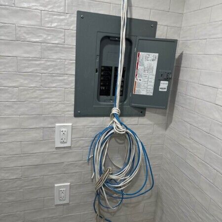 Electrical panel with hanging wires for pool or outdoor setup.