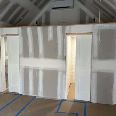 Interior view of a cabana under construction with drywall and door openings.