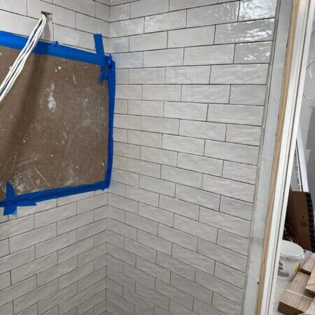 Interior of a cabana with tiled walls and construction materials present.