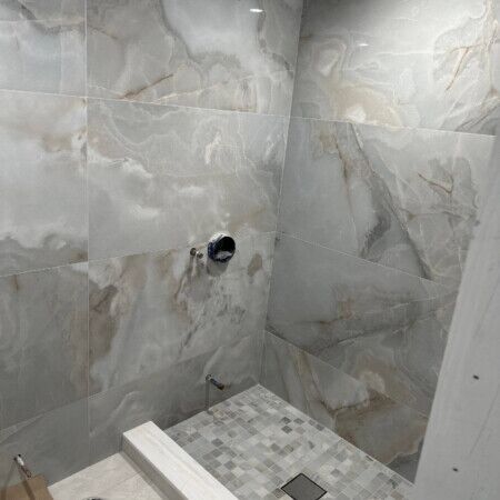 Luxury outdoor shower with marble tiles and mosaic floor.