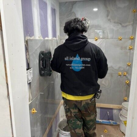 Worker installing tiles in outdoor pool area on Long Island.