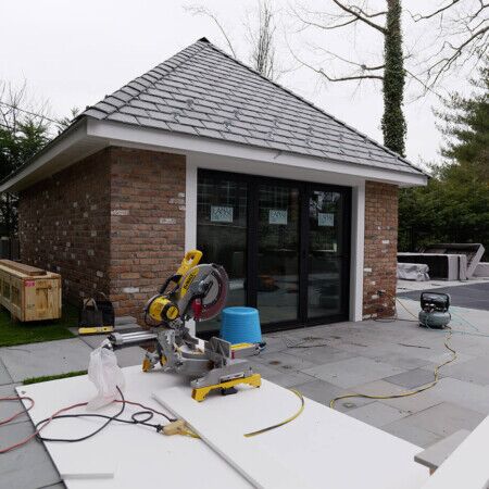 Construction of a cabana with brick walls and sliding glass doors in progress.