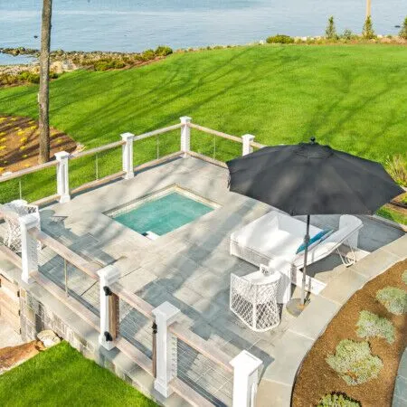 Beautiful backyard with inground pool, outdoor furniture, and ocean view in Long Island.