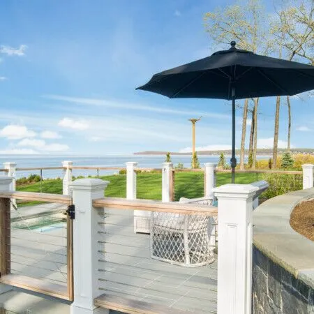 Scenic outdoor space with ocean view, umbrella, and landscaped yard.