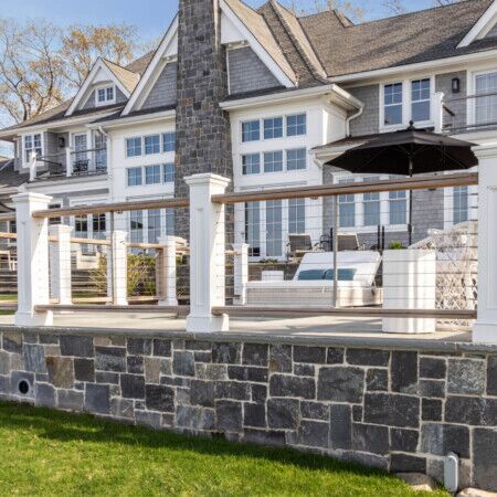 Elegant outdoor deck with seating and umbrella at a luxury home in Long Island.