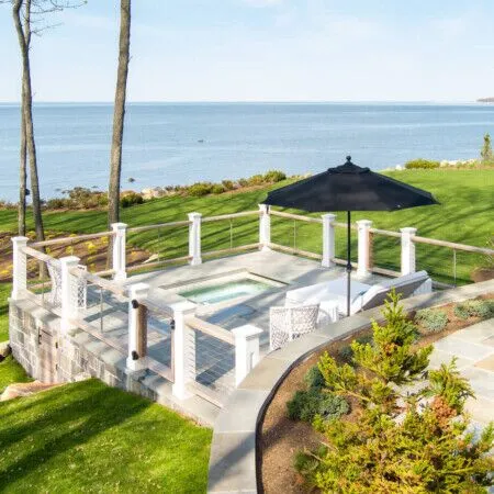 Beautiful outdoor pool area with ocean view and lush landscaping.