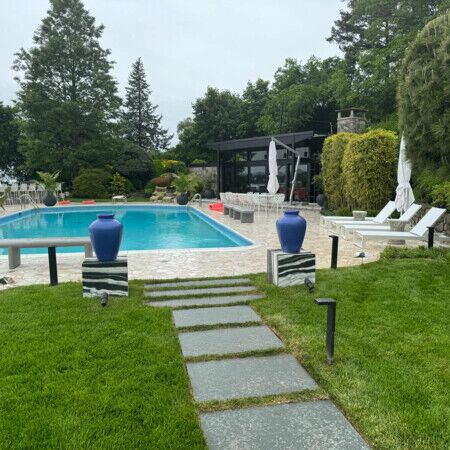 Elegant backyard with inground pool, outdoor seating, and landscaped garden in Long Island. Beautiful backyard with inground pool, outdoor furniture, and lush greenery.