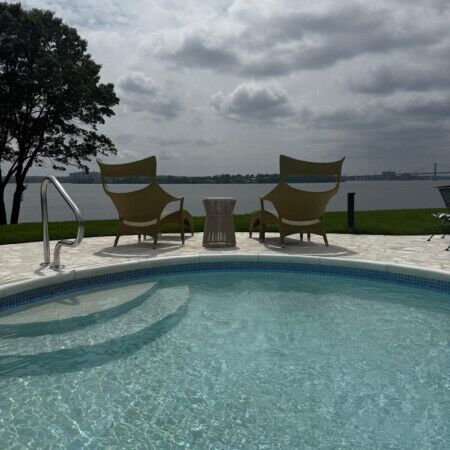 Relaxing outdoor pool area with chairs and scenic water view in Long Island, perfect for outdoor leisure and gatherings. Inground pool with outdoor chairs and scenic water view in Long Island.