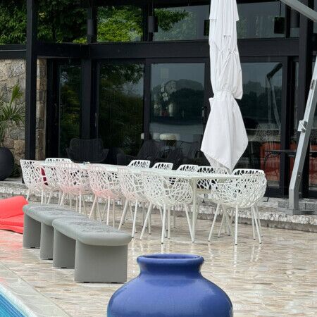 Elegant outdoor dining setup with white chairs, umbrellas, and poolside lounge area in Long Island. Modern outdoor dining area with poolside seating and umbrellas.