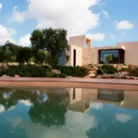 Luxury modern house featuring a pool, outdoor seating, and scenic landscape on Long Island. Contemporary house with pool, outdoor furnishings, and natural landscape.