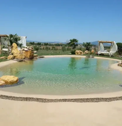 Inground pool with natural rock features and outdoor furnishings in Long Island.