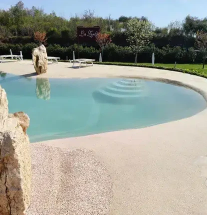 Elegant inground pool with natural rock accents and lush landscaping in Long Island. Beautiful inground pool with natural rock features and outdoor furnishings.