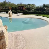 Elegant inground pool with natural rock accents and lush landscaping in Long Island. Beautiful inground pool with natural rock features and outdoor furnishings.